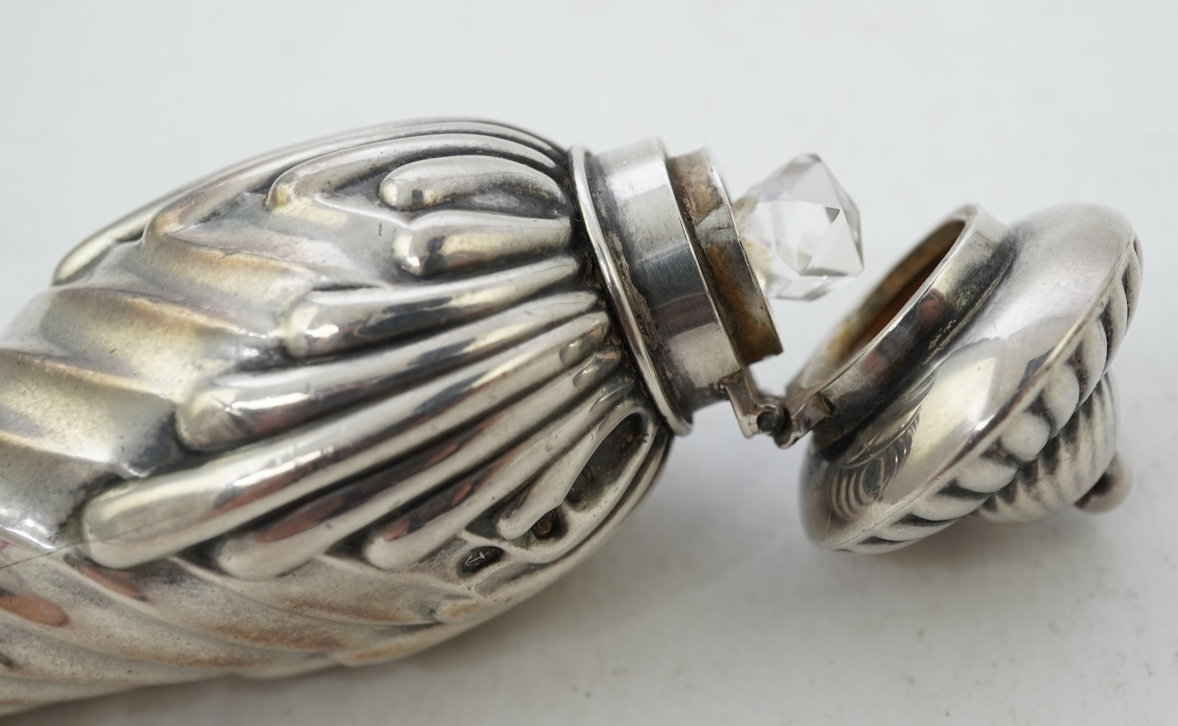 A late Victorian silver scent flask, of spiral tear drop form, with hinged cover and glass stopper